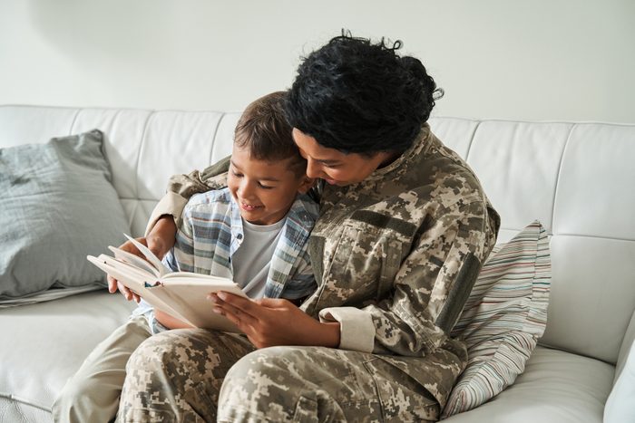 Multiracial woman wearing uniform reading book while sitting at the sofa