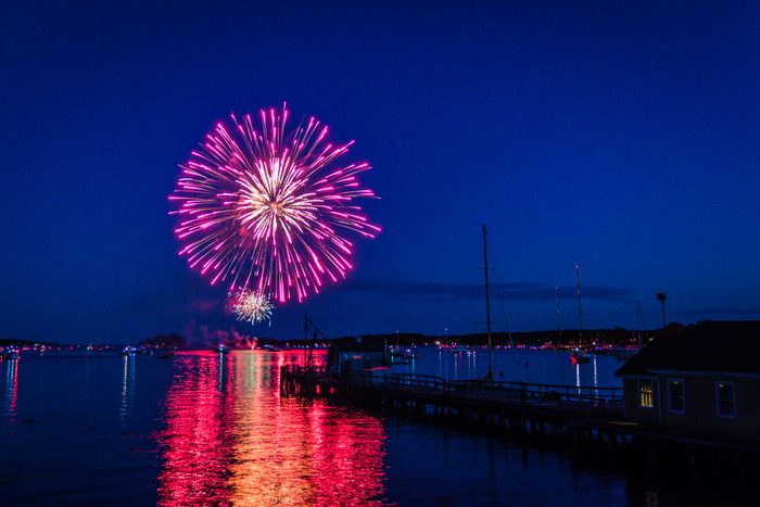 Boats in the calm and beautiful Boothbay Harbor with fireworks launching on the Fourth of July