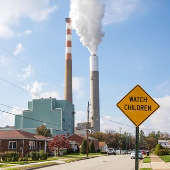 A view of the smoke stacks of the 47-year old Cheswick coal-fired power plant in Springdale, Pennsylvania behind a residential neighborhood with a "Watch Children" sign in the foreground.