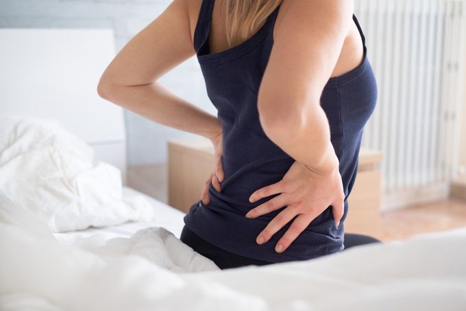 Painful woman awakening and feeling back pain