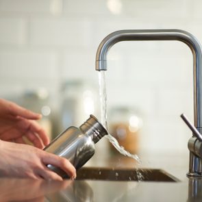 Cleaning a plastic free reusable water bottle in kitchen sink.