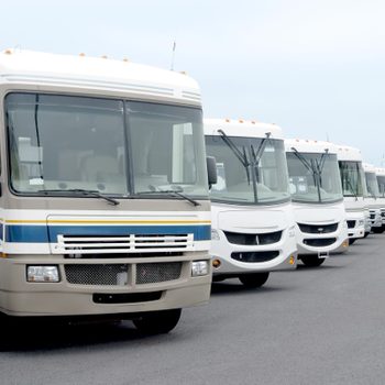a row of class A motorhomes for sale in a parking lot