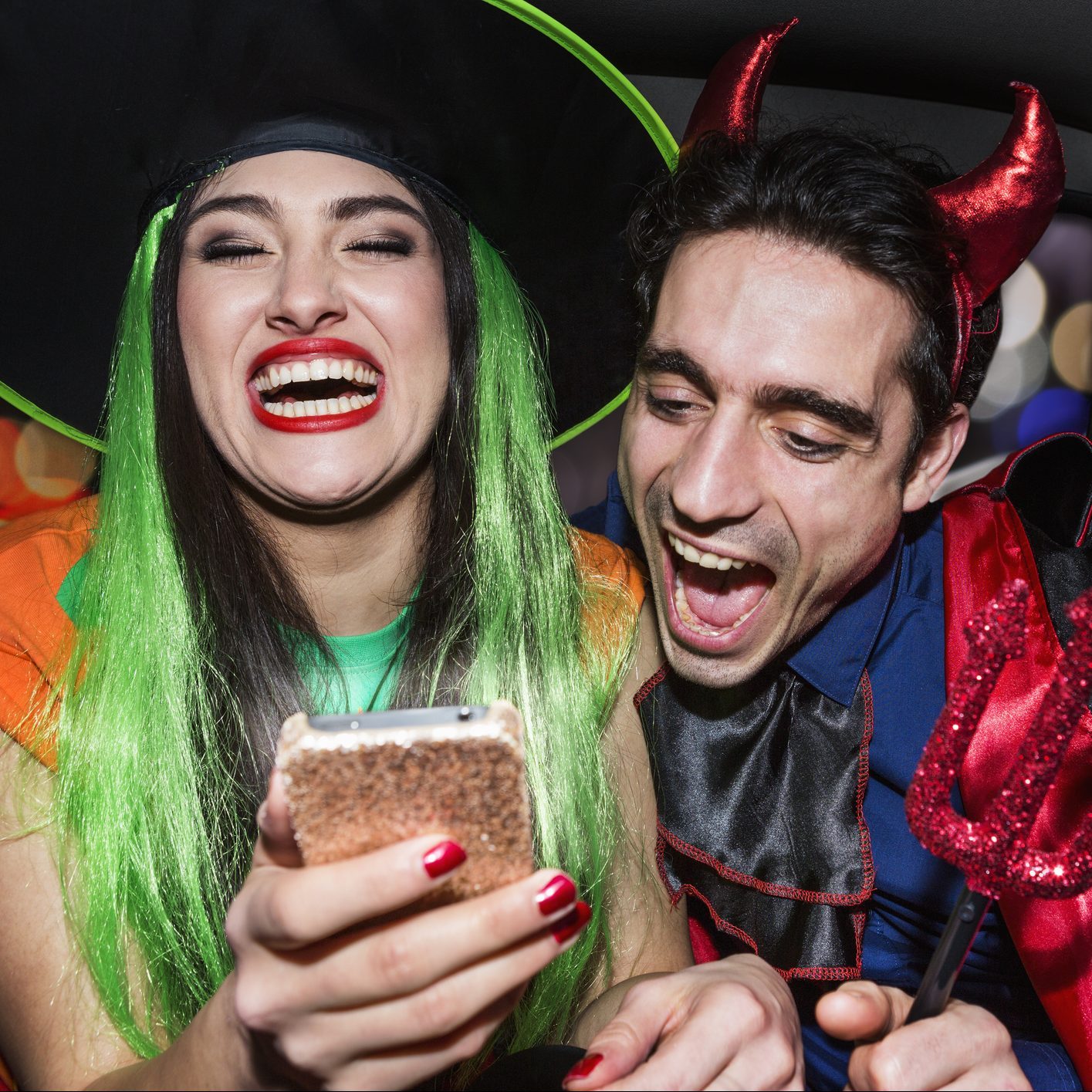 Halloween witch and devil laughing in back of car