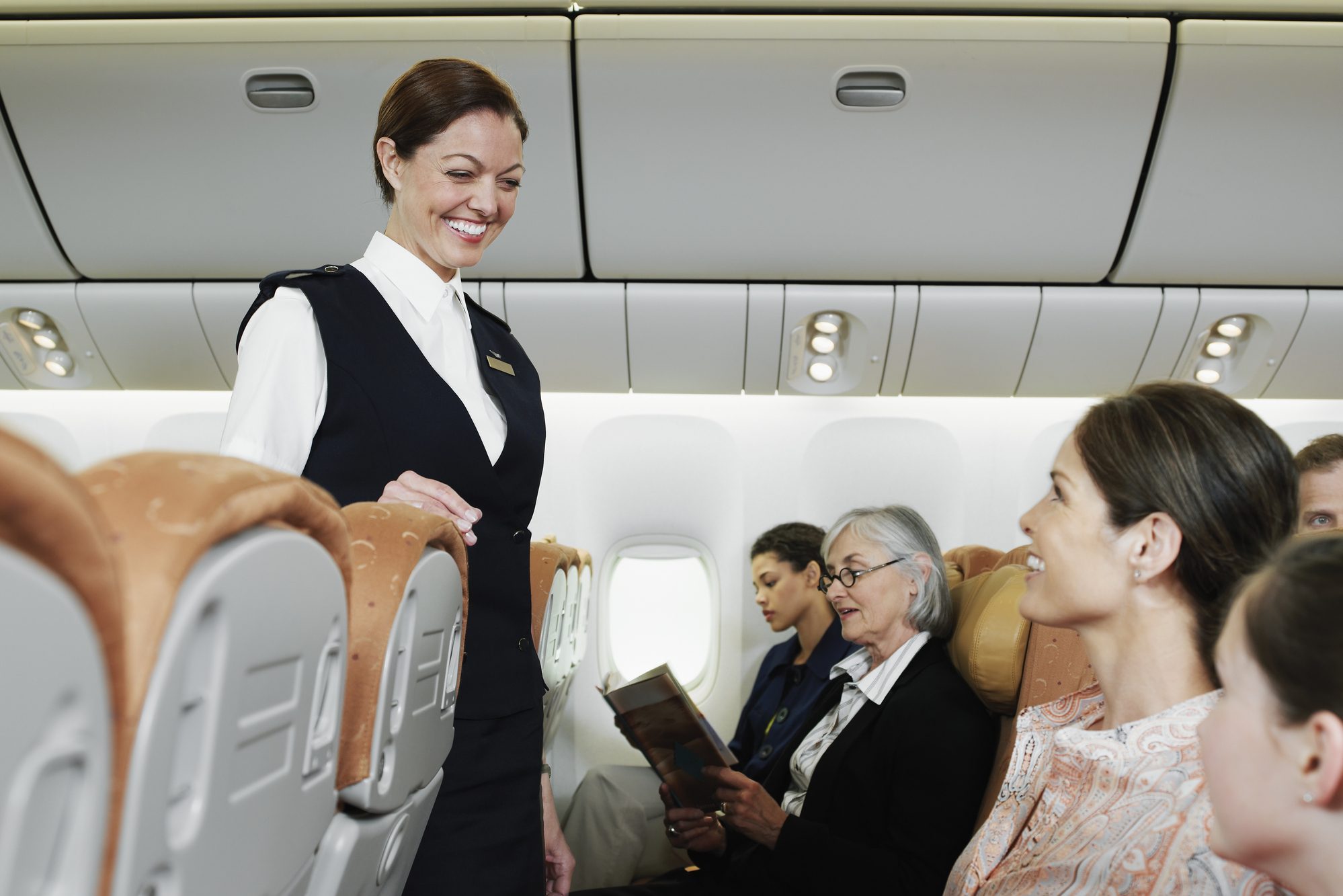 Flight attendant talking with passengers including child (10-11) on airplane