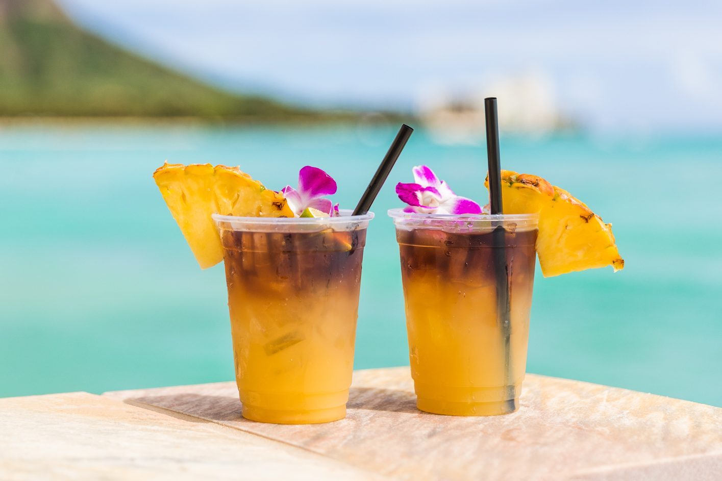 Hawaii mai tai drinks on waikiki beach bar travel vacation in Honolulu, Hawaii. Famous hawaiian drink cocktails with view of ocean and diamond head mountain, Hawaii tourist attraction
