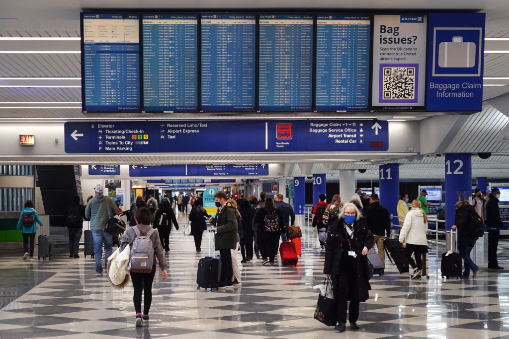 Travelers collect their luggage at baggage claim after arriving at O'Hare International Airport on March 11, 2022 in Chicago, Illinois
