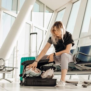 blonde woman packing her carry on in airport waiting area space