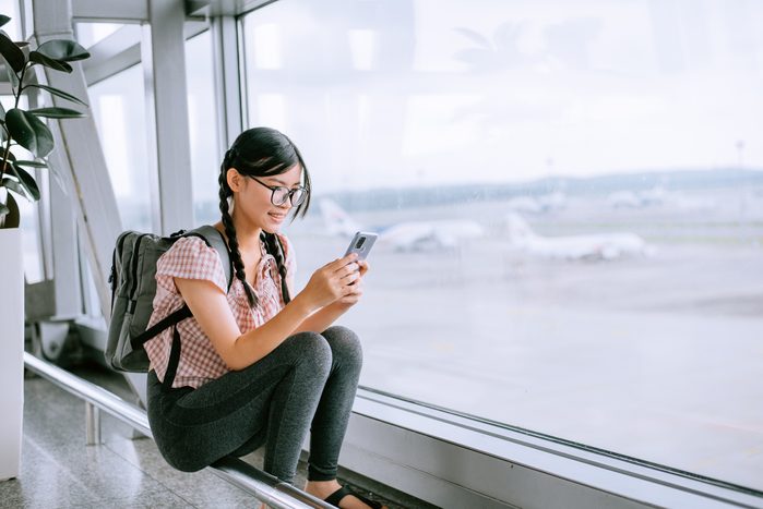 Tween girl looking at smartphone at airport