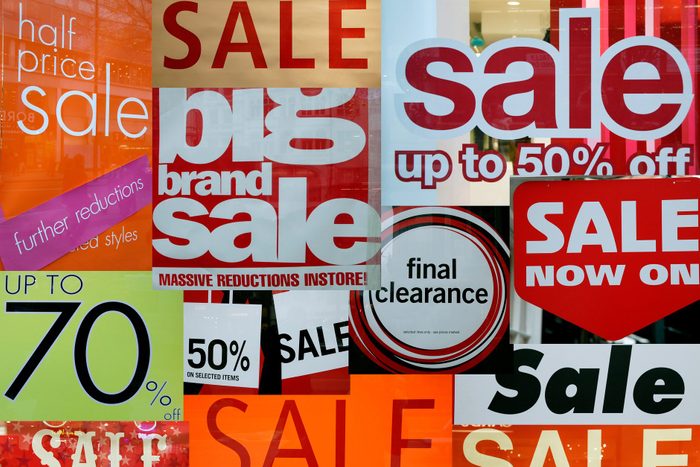 store window covered in a variety of Sale signs