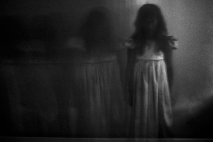 Double exposure of spooky girl against wall at home