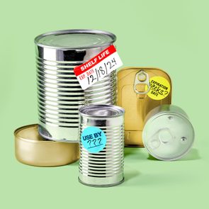 Canned Food arranged on a green background. some cans have expiration stickers