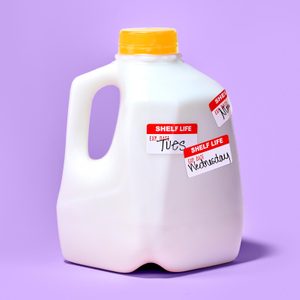 gallon of milk on purple background. the container has three expiration stickers added, each with a different day of the week written on it