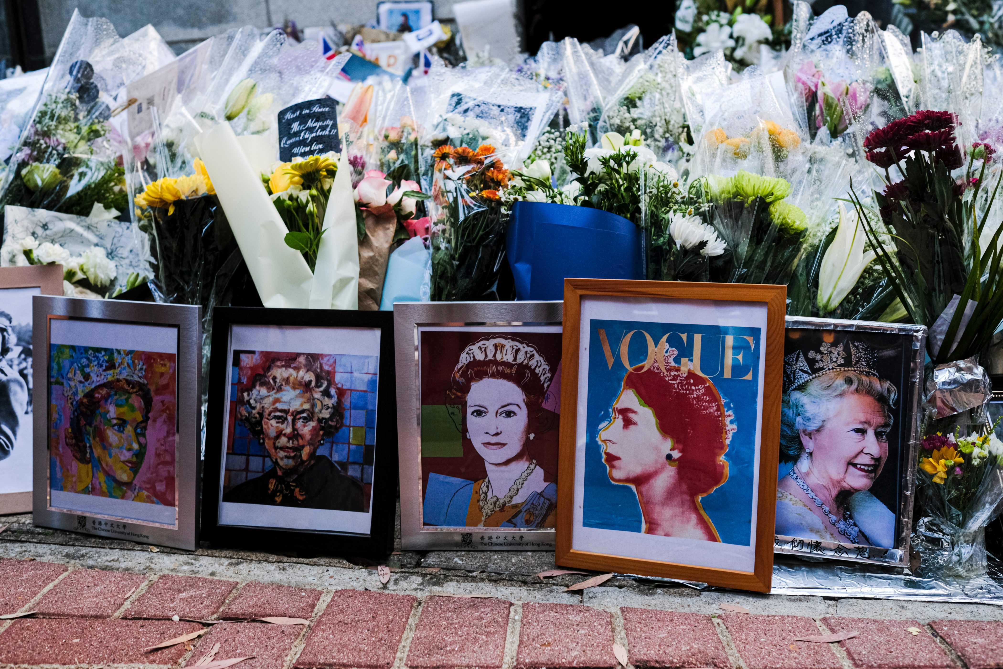 Flowers and tributes are placed on the ground in memory of Queen Elizabeth II outside the British Consulate General Hong Kong on September 16, 2022 in Hong Kong, China. Queen Elizabeth II died at Balmoral Castle in Scotland aged 96 on September 8, 2022, and is survived by her four children, Charles, Prince of Wales, Anne, Princess Royal, Andrew, Duke Of York and Edward, Duke of Wessex. Elizabeth Alexandra Mary Windsor was born in Bruton Street, Mayfair, London on 21 April 1926. She married Prince Philip in 1947 and acceded the throne of the United Kingdom and Commonwealth on 6 February 1952 after the death of her Father, King George VI. Queen Elizabeth II was the United Kingdom's longest-serving monarch. (Photo by Sawayasu Tsuji/Getty Images)