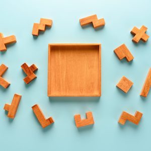 pieces of a wooden iq puzzle scattered around the puzzle frame. blue background