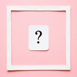 Card of question mark in white frame on pastel pink background. Soft light color. Women issues. Problem and solution concept.