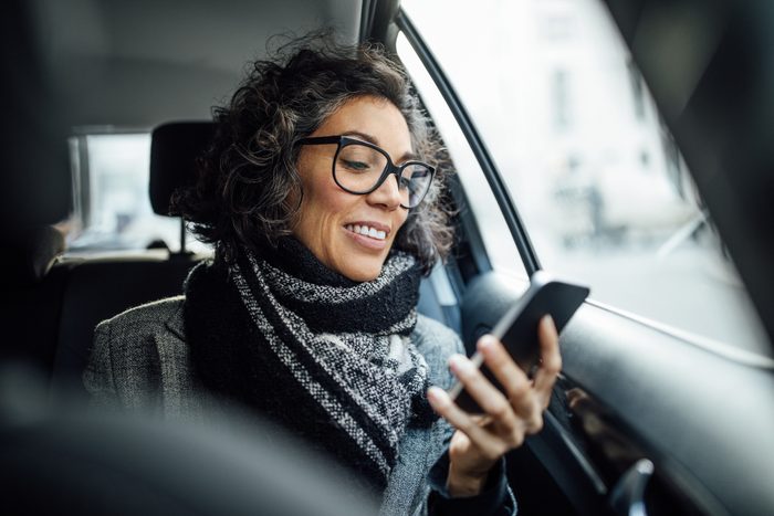 woman using phone while traveling by a taxi