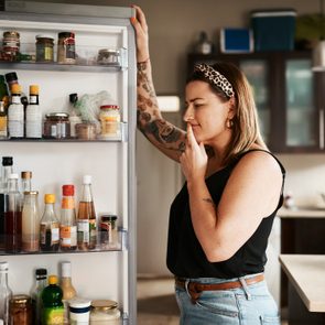 young woman searching inside a refrigerator at home