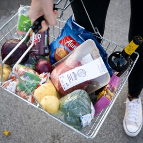 hands holding a grocery basket filled with food