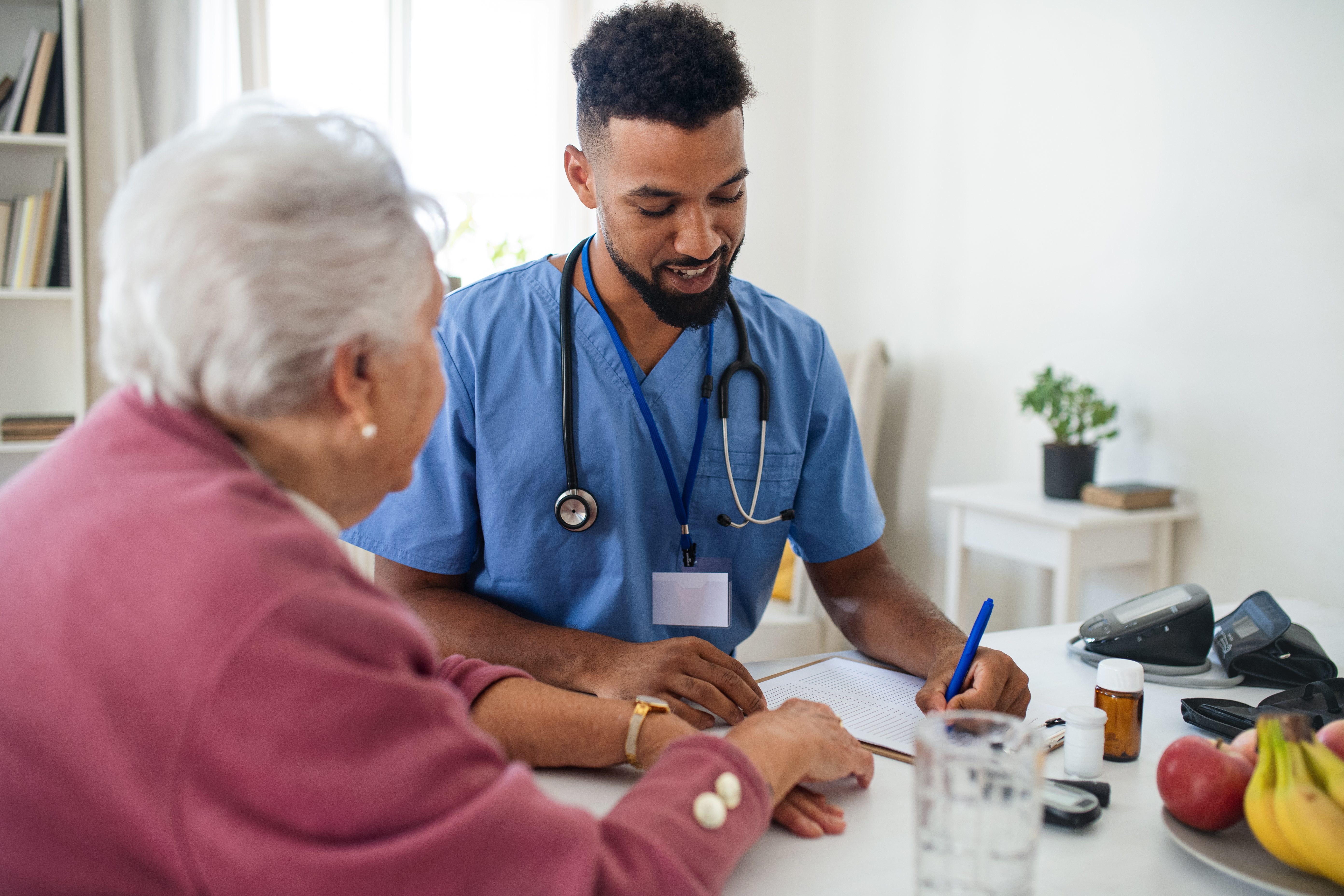 Healthcare Worker Or Caregiver Visiting Senior Woman Indoors At Home, Explaining.