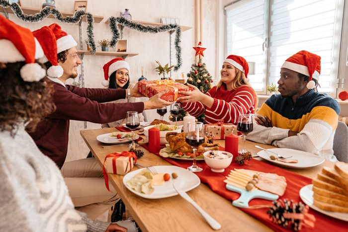 Group Of Friends Exchanging Gifts At Christmas Lunch