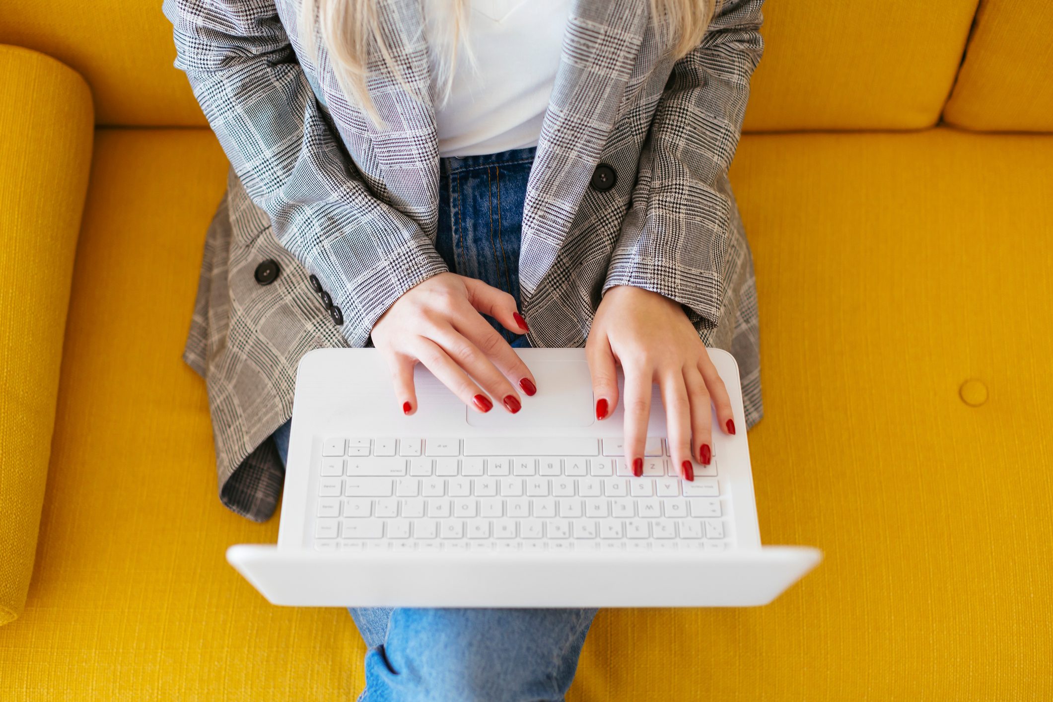 Business woman sitting on yellow couch, using laptop