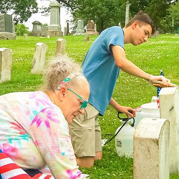 Madonna White and Aaron Schultz plant American flags near each cleaned headstone.