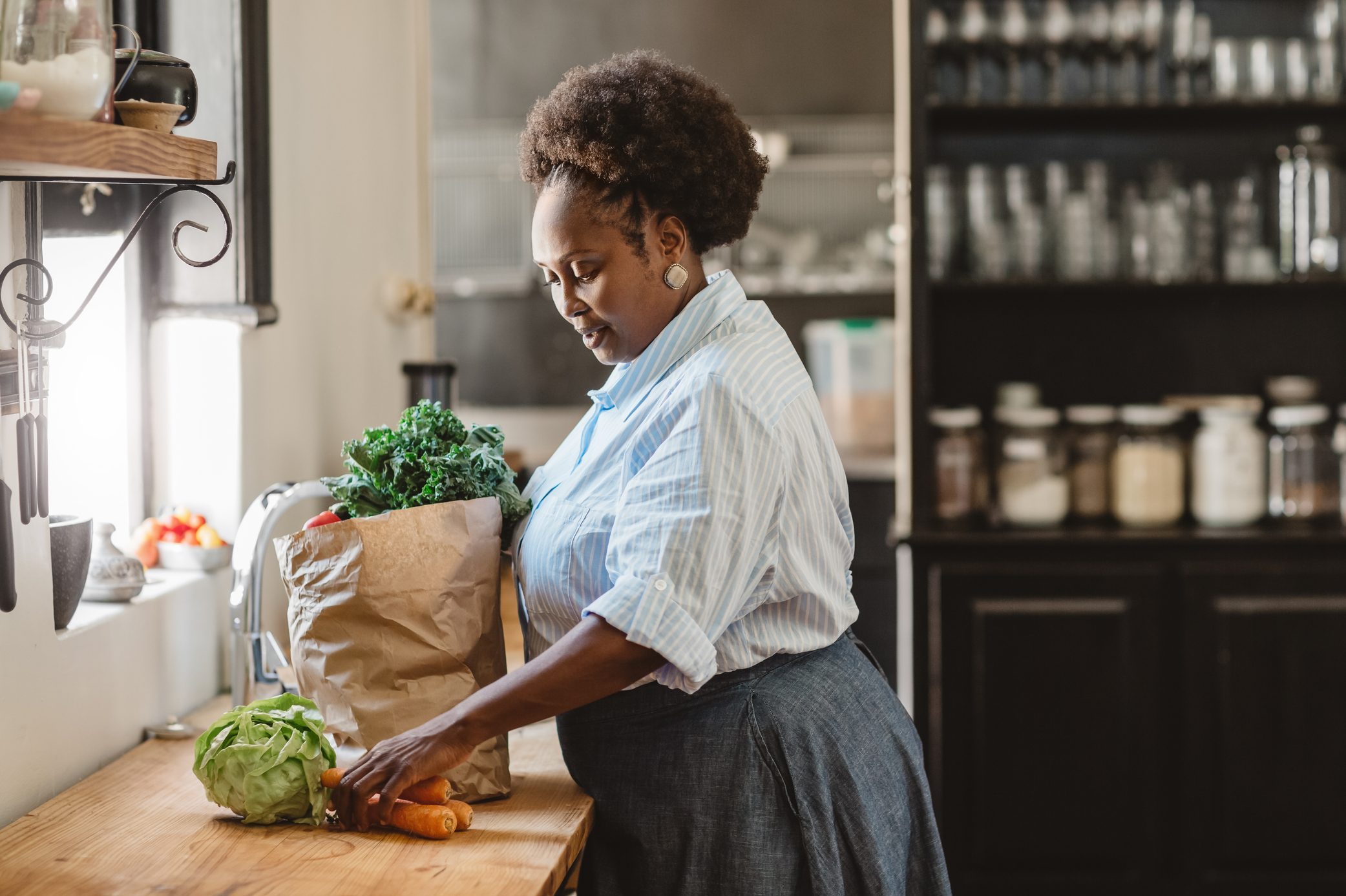 Smiling African American woman unpacking groceries in her kitchen