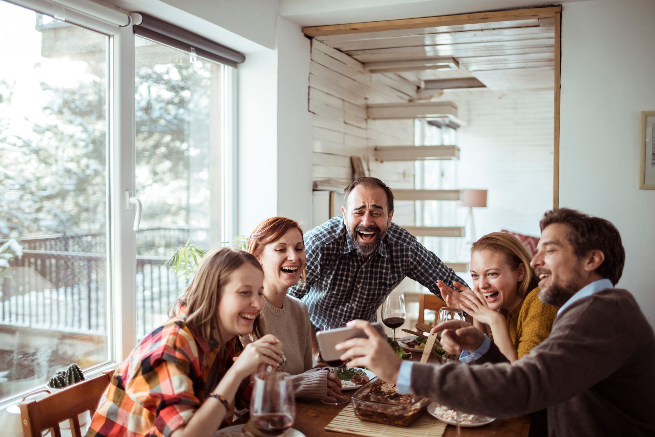 friends laughing at something on someones phone at the dinner table