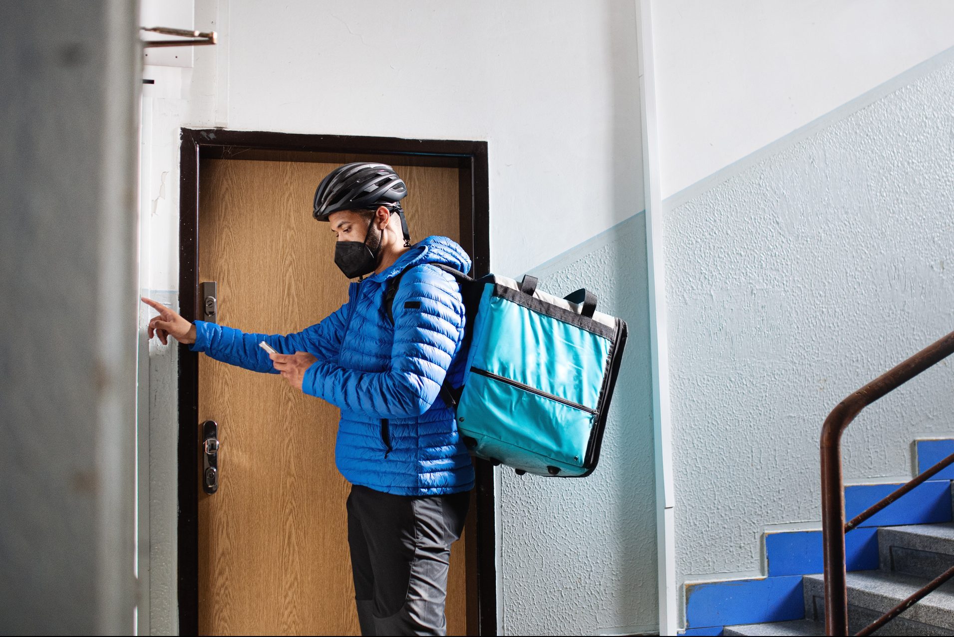 Man indoors by front door in block of flats, food delivery and coronavirus concept.