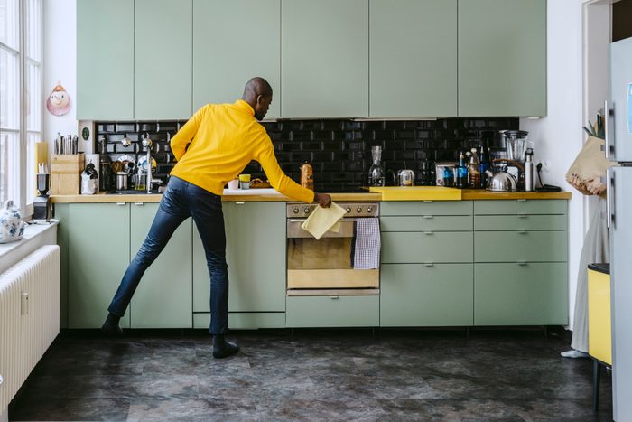 Full length of mid adult man doing chores in kitchen at home