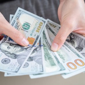 Close up of someone hands holding and counting American dollar banknotes in her hand.