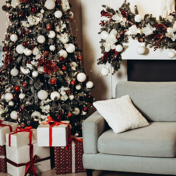 Sofa in xmas room with of gift boxes under new year tree.
