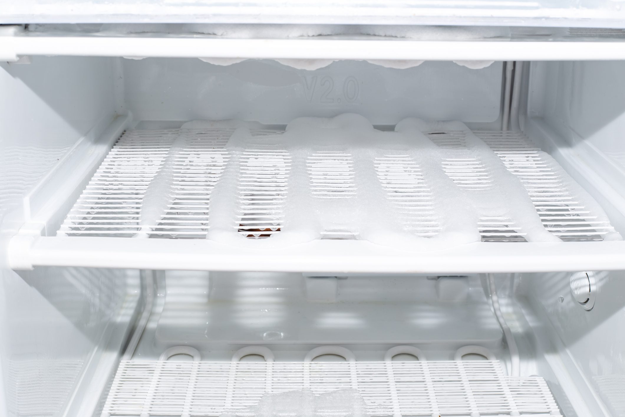 Freezer with shelves covered with ice. Freezer defrosting and care