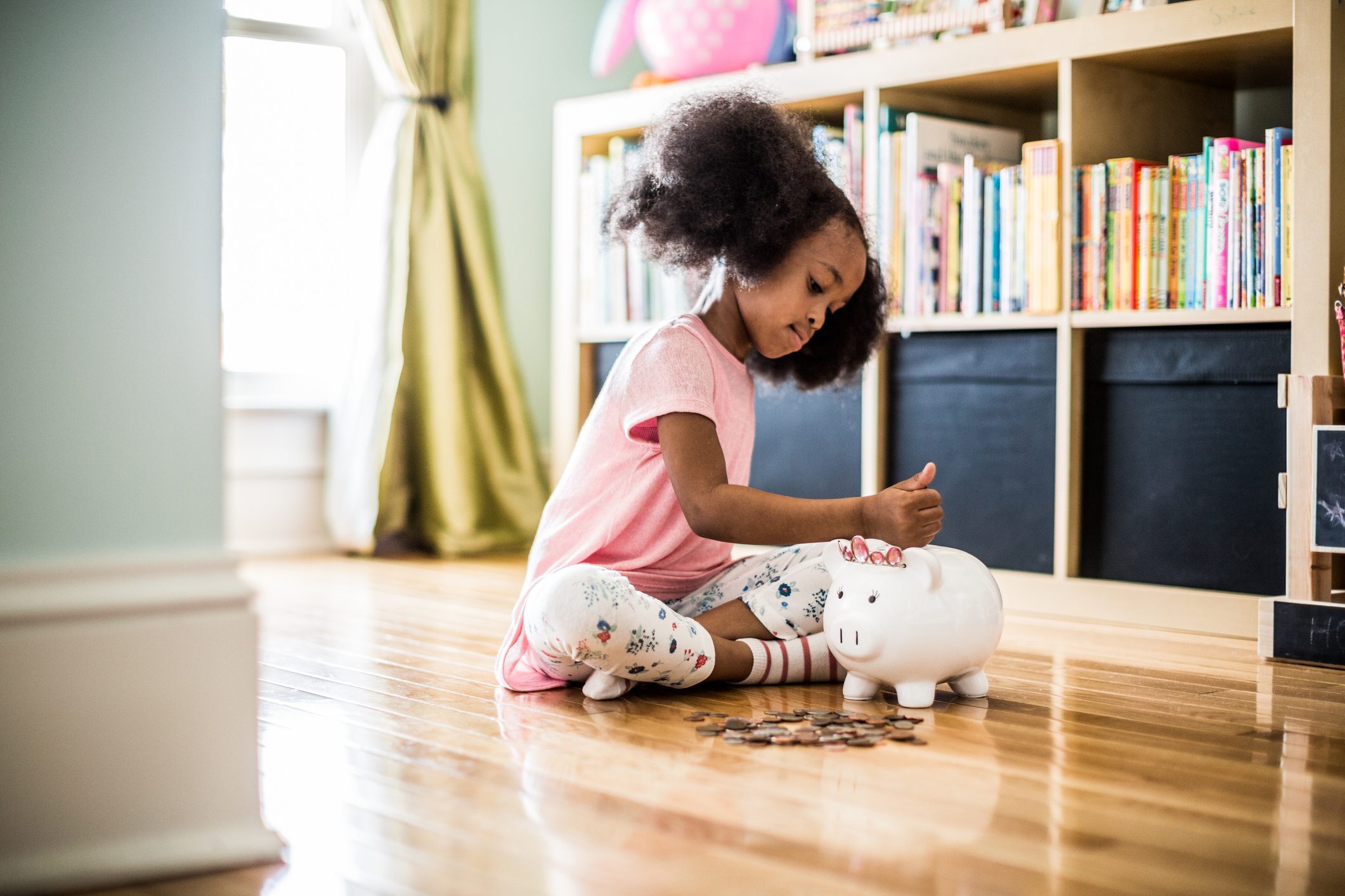 girl putting money in piggybank