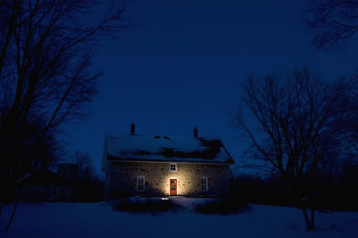 Illuminated Christmas wreath on door of stone house at dusk in Cedarburg, WI