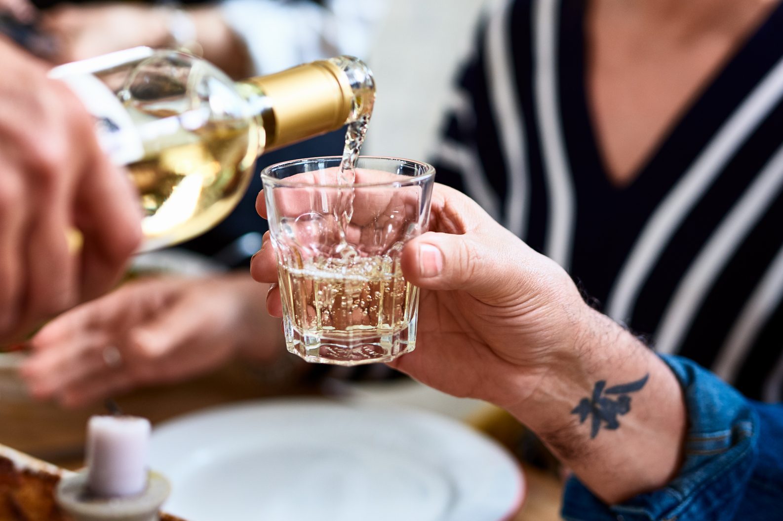 Close up of man with tattoo on wrist being served wine