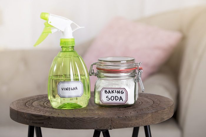 Using baking soda Sodium bicarbonate and white vinegar for home cleaning. White vinegar in spray bottle and baking soda in glass jar.