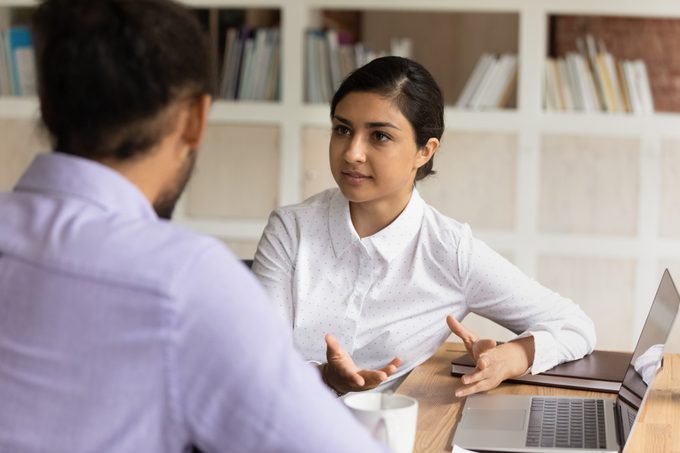 Concentrated two mixed race managers discussing online project.