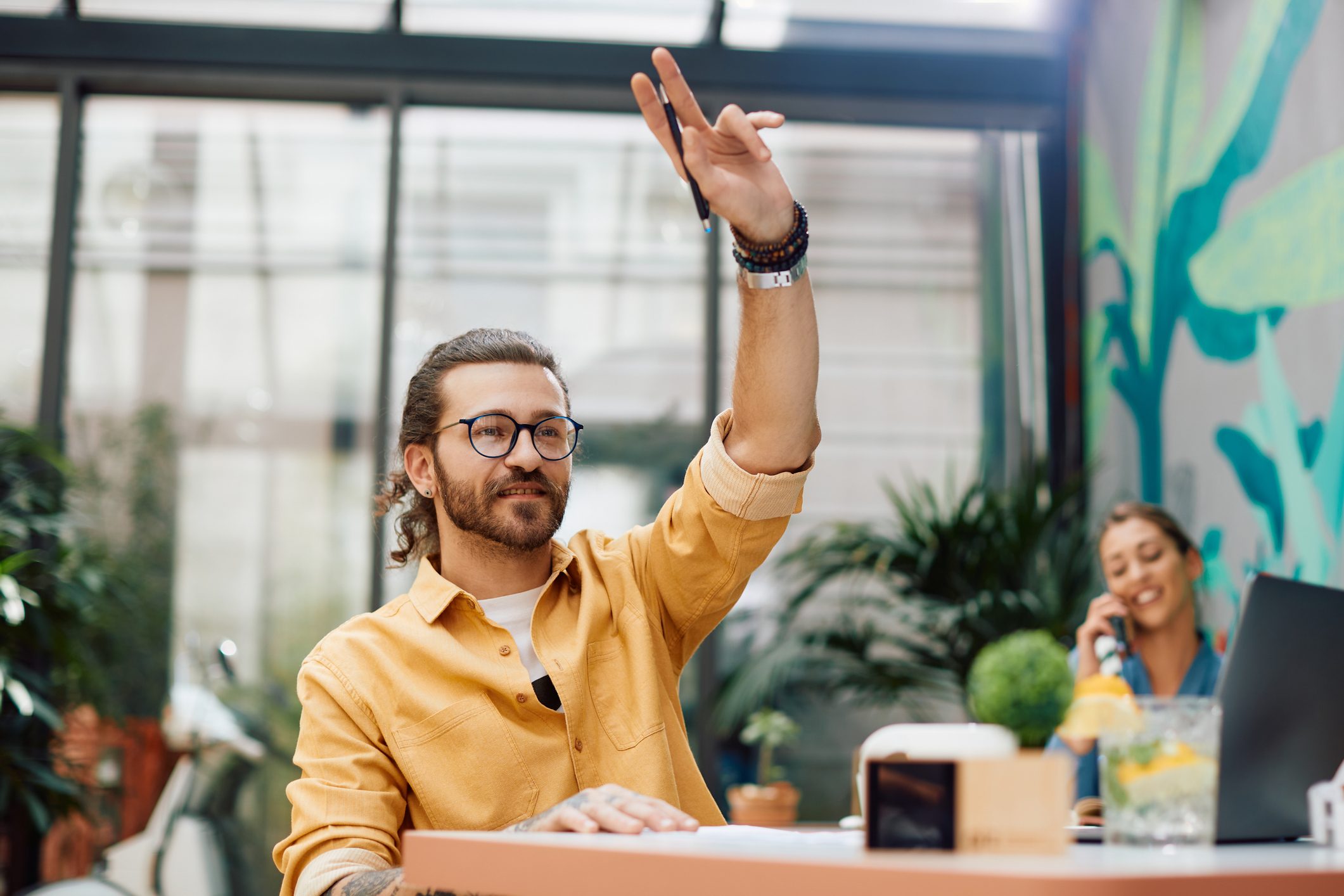 Young man with hand raised calling the waiter in a cafe.