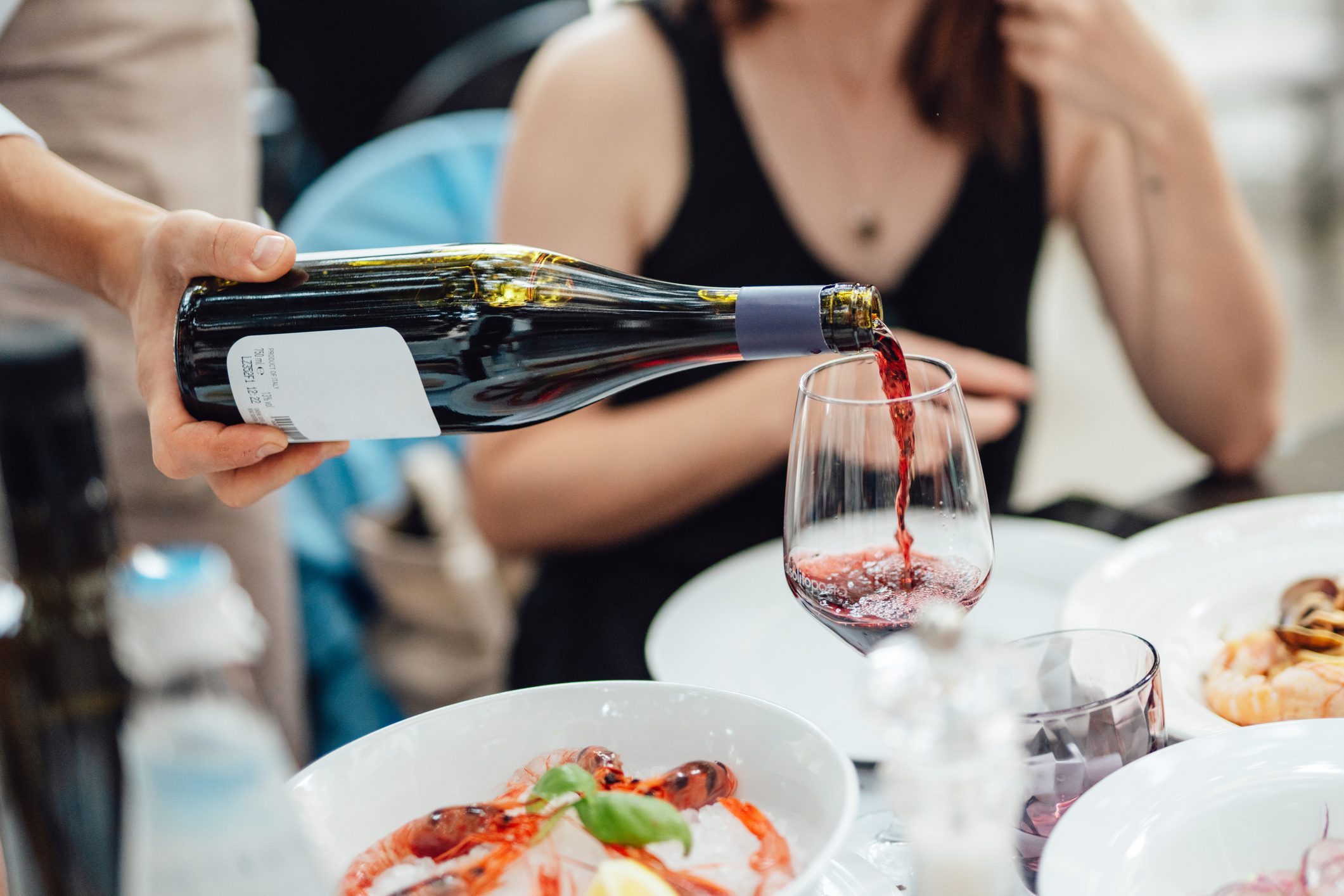 Waiter pouring wine for customers in luxury outdoor restaurant