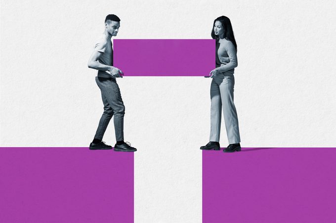 Man and woman holding block while standing at the edge of cliff