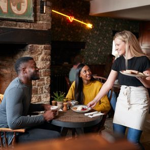 Waitress Working In Traditional English Pub Serving Breakfast To Guests