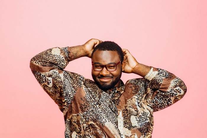 Portrait of a sweet smiling man in leopard print shirt and arms up