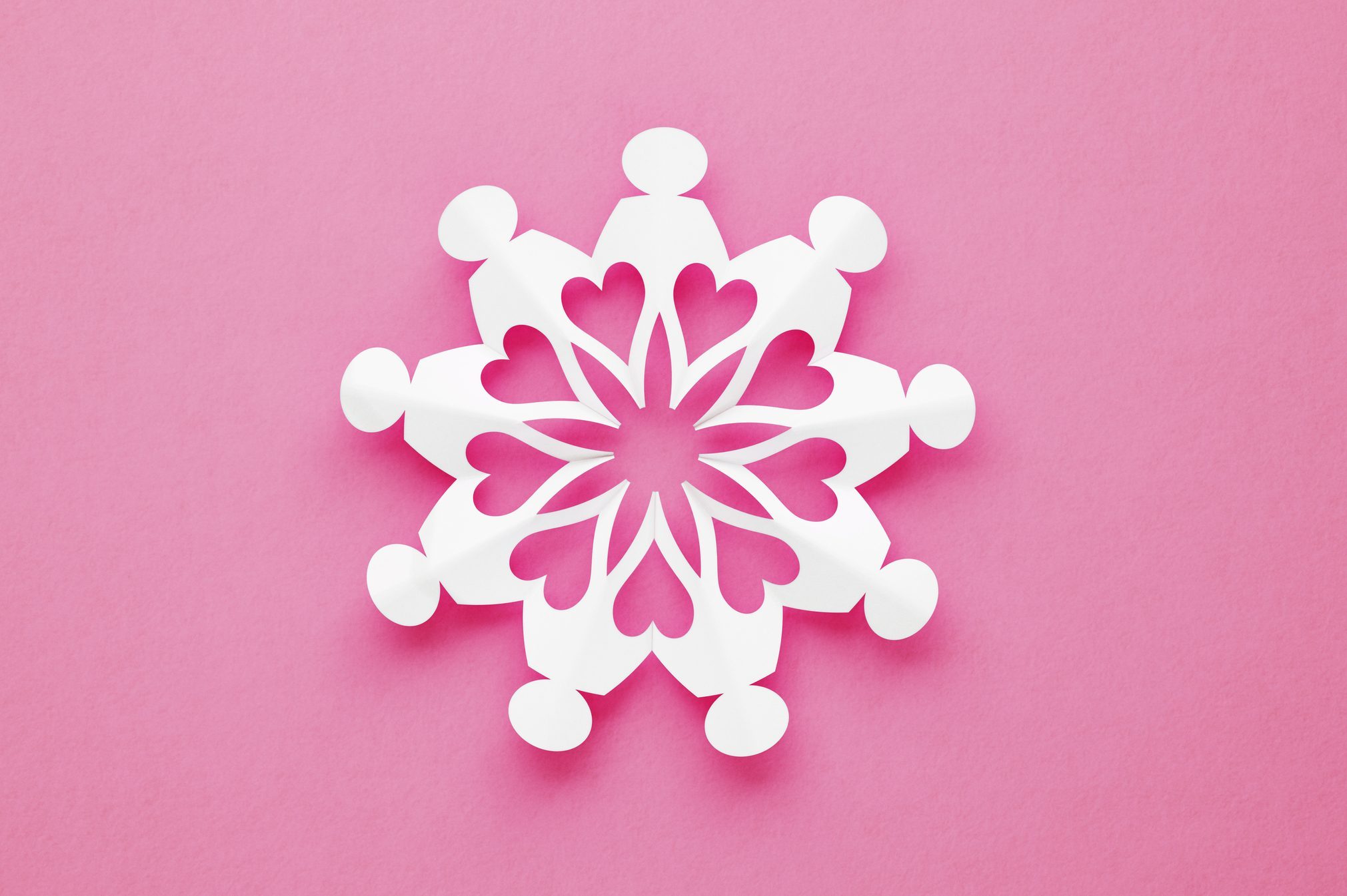 Chain Of Volunteer People Made of Paper creating a snowflake-like pattern on Pink Background