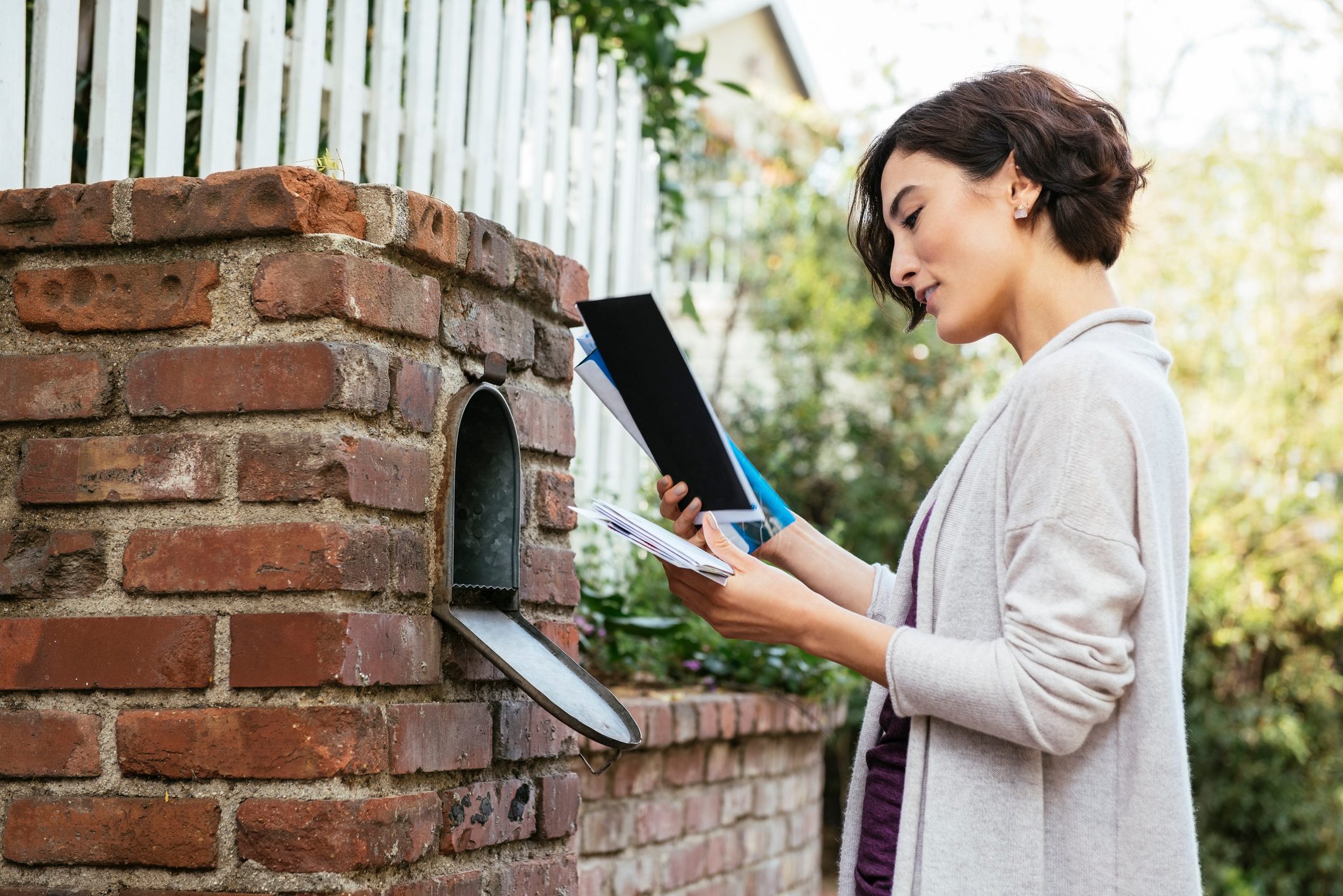 Side view of beautiful young woman at mailbox
