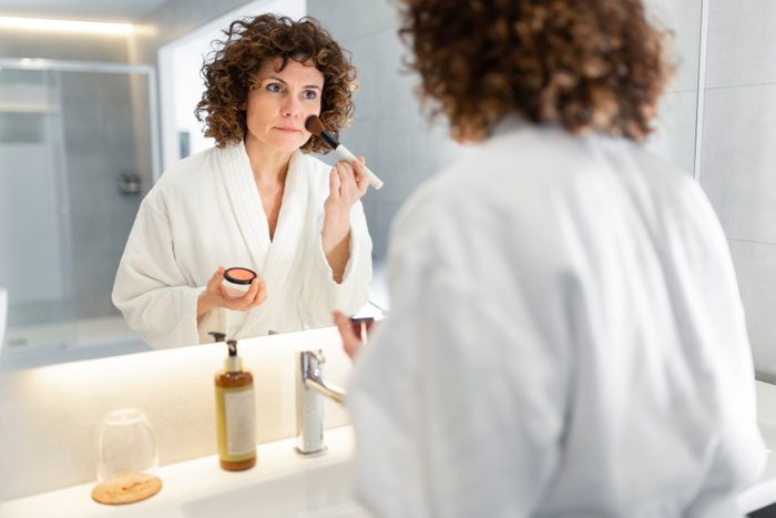 Beautiful woman applying powder from make-up brush in bathroom