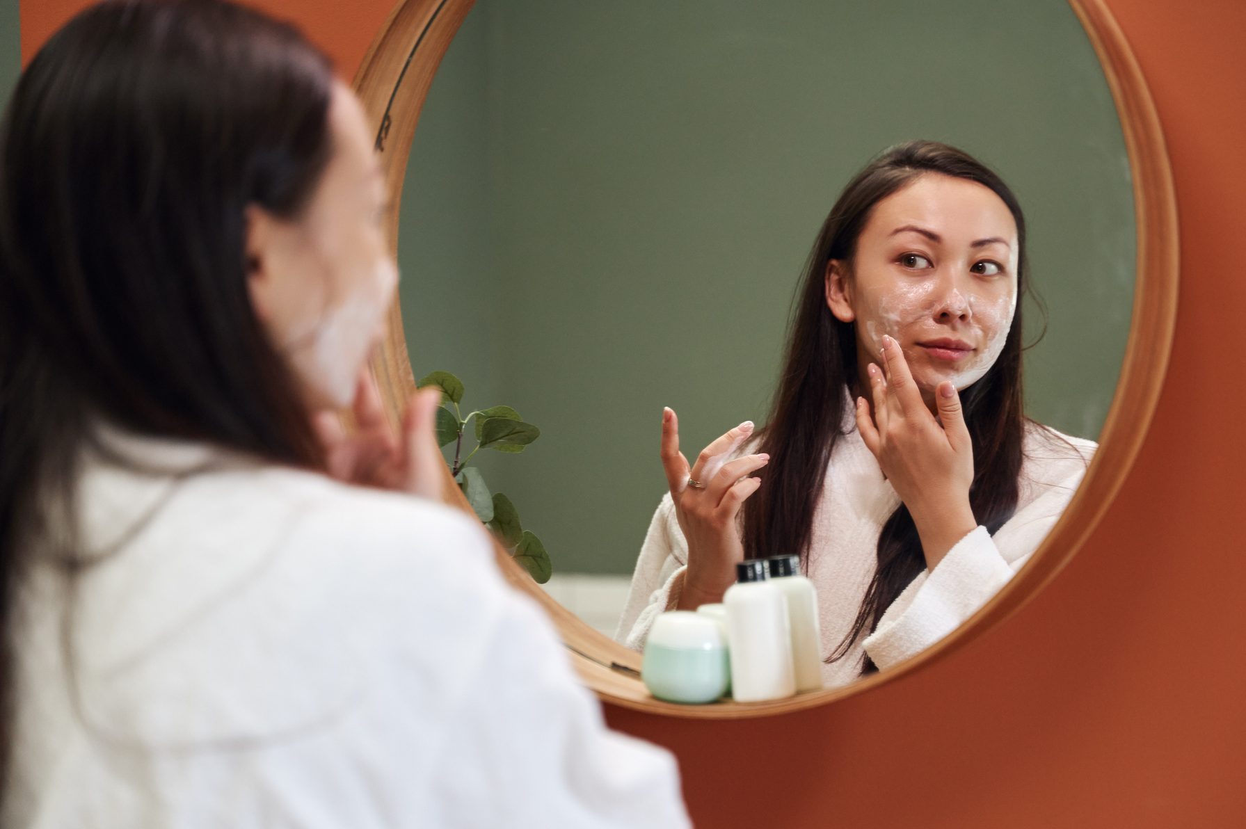 Asian woman applying moisture cream at her face