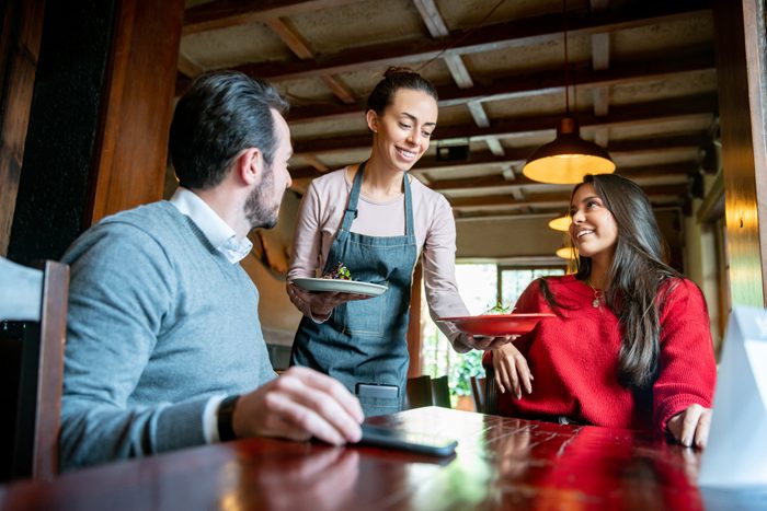 Waitress serving food to customers at a restaurant