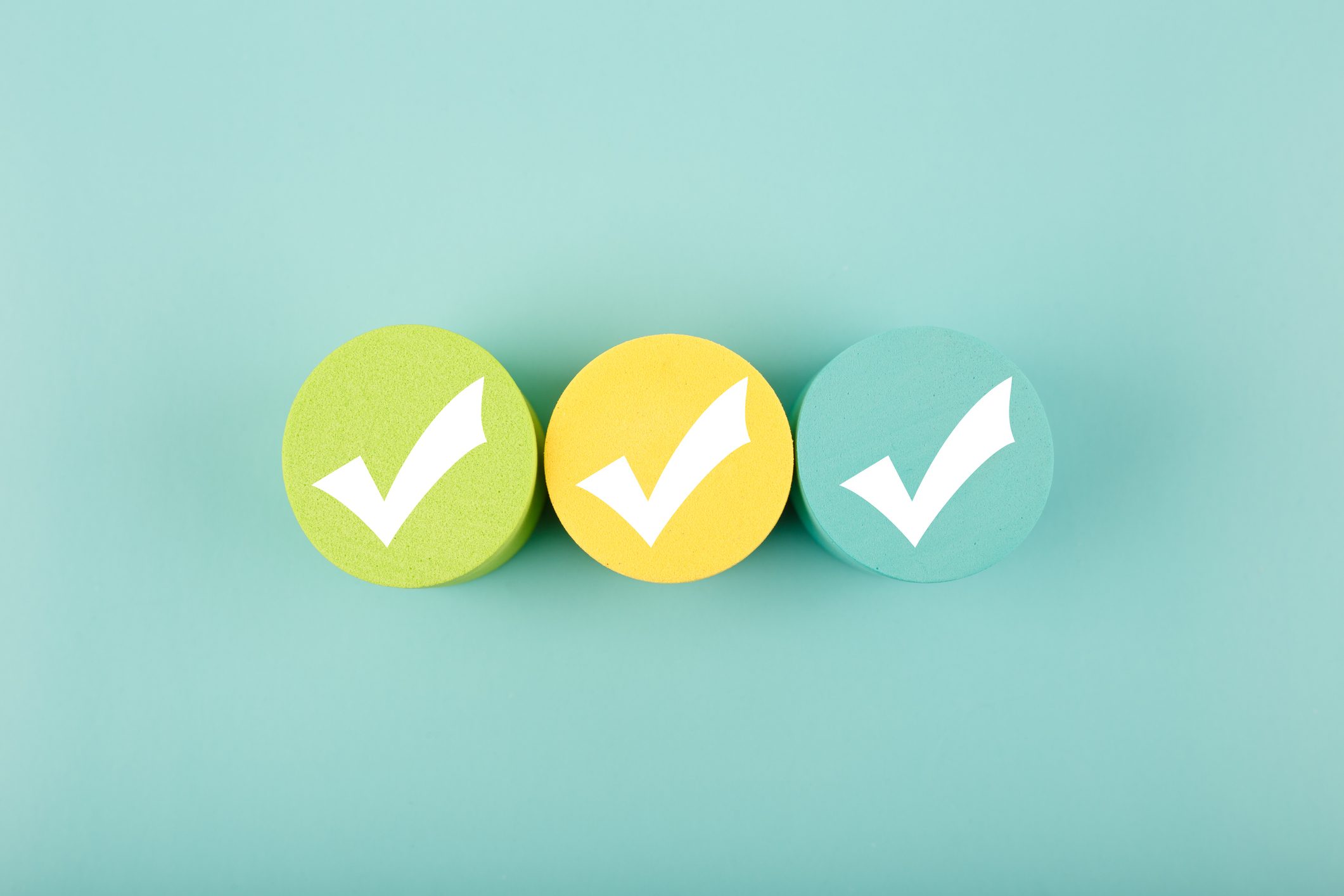 Three white checkmarks on colorful circles against bright aqua blue background