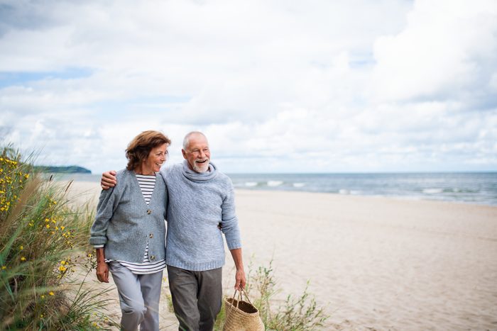 Senior couple in love on walk on beach.